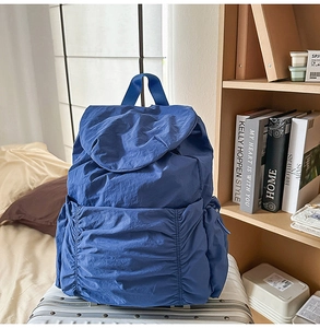 Détail d'un sac à dos en nylon bleu foncé avec cordon sur une valise blanche