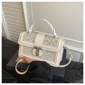 Detail of elegant jacquard handbag with floral patterns and polished metal twist lock