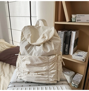 Détail du sac à dos crème à cordon avec texture en nylon froissé sur une valise