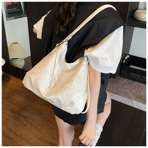 Detailed view of cream hobo shoulder bag featuring intricate jacquard texture on wide strap