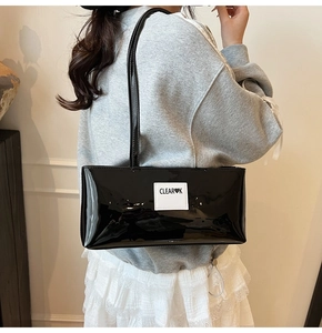 Glossy black patent leather shoulder bag with white heart logo patch detail view