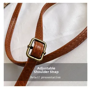 Detail of adjustable dark brown leather shoulder strap with vintage bronze buckle