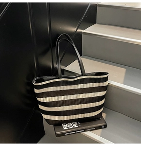 Nahaufnahme der gewebten schwarz-weiß gestreiften Shopper-Tasche mit schwarzen Lederriemen
