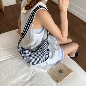 Detail of gingham moon bag with striped adjustable strap and zipper closure
