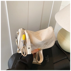 Detail of cream white pleated PU leather crossbody bag with logo and yellow charm