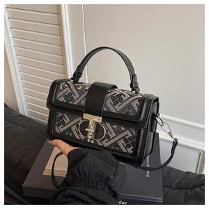 Detail of blue geometric jacquard fabric and gold D-ring twist lock on square bag