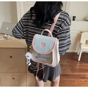 Detail of a mini pastel backpack with heart cutout and white plush pendant accessory
