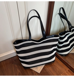 Detail der großen gewebten Shopper-Tasche mit schwarz-weißen Streifen und Ledergriffen
