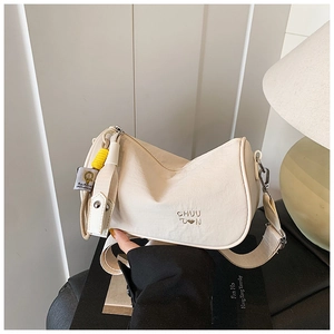 Detail of beige nylon crossbody bag featuring heart embroidery and wide shoulder strap