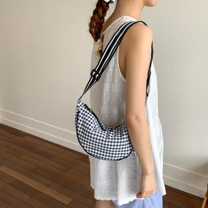 Macro shot of checkered crescent bag with adjustable striped shoulder strap detail