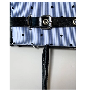Detailed close-up of blue striped bag with black heart prints and silver metal buckle