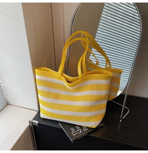 Detail der gelb-weiß gestreiften gewebten Shopper-Tasche mit Ledergriffen im Regal