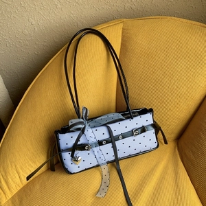 Detail of blue striped bag with black heart patterns and decorative silver pendant