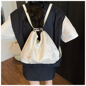 Detailed back view of model wearing a white embroidered backpack with floral textures