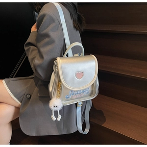 Detail of silver mirror backpack with pink heart, logo embroidery and plush pendant