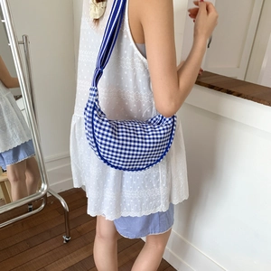 Blue and white plaid canvas hobo bag styled on model with a wide striped shoulder strap