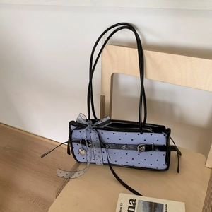 Close-up of heart-patterned baguette bag featuring leather buckle and silver heart charm