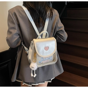 Close-up of holographic silver mini backpack featuring pink heart detail and plush charm