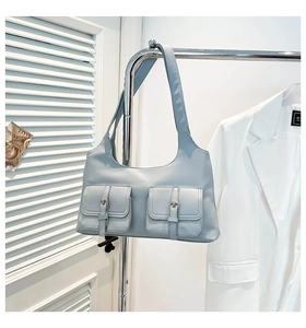 Détail du sac porté épaule bleu clair avec deux poches à rabat et bandoulière large