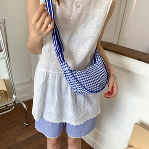 Detailed close-up of blue and white checkered crescent canvas bag with striped strap