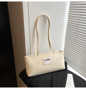 Close-up of CLEAR♥K logo on creamy white patent leather rectangular shoulder bag
