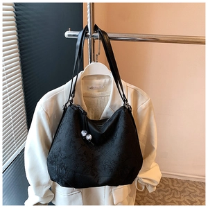 Detail of black embroidered rose patterns and beaded zipper on high-capacity tote bag