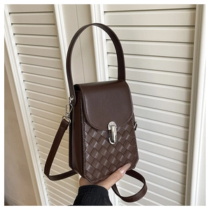 Detail of dark brown leather handbag featuring woven texture and silver twist lock