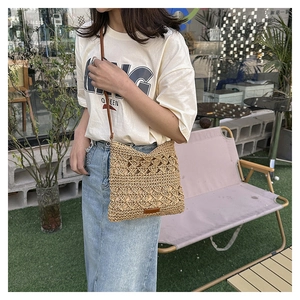 Detail showing handwoven hollow crochet pattern and brown faux leather strap of the bag