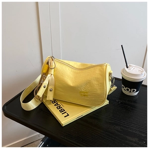 Detail of bright yellow textured crossbody bag on a book with coffee cup scene