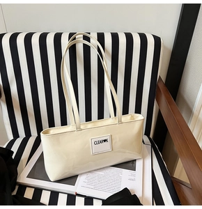 Detail of glossy cream rectangular tote bag with decorative patch on a stylish background