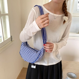 Lifestyle view of the blue and white checkered crescent canvas bag with a wide strap
