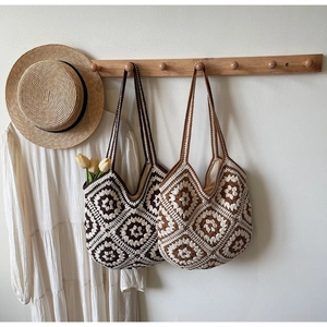 Détail de sacs cabas en crochet faits main avec motifs floraux sur supports en bois