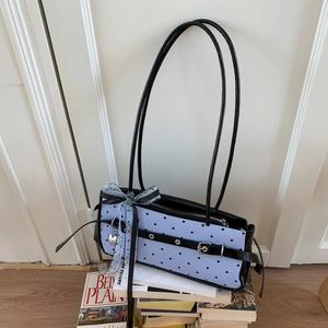 Detail of light blue striped shoulder bag with heart print and decorative ribbon bow