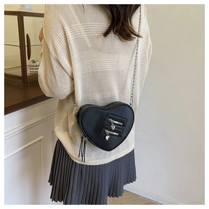 Detail of a black heart-shaped crossbody bag with silver tassels and metal chain strap