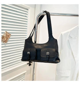 Détail du sac porté épaule en cuir noir avec deux poches à boucles argentées devant