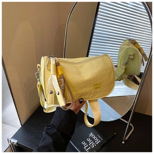 Detailed macro shot of yellow pleated barrel bag with wide strap and reflective texture