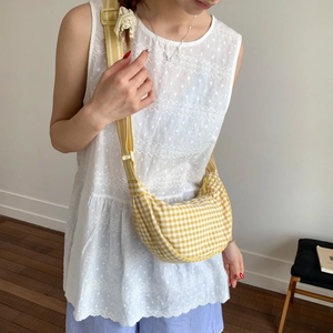 Detail of yellow checkered crescent bag with adjustable wide strap shown on model