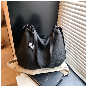 Detail of black floral jacquard tote bag with bead pendant and metallic ring accents