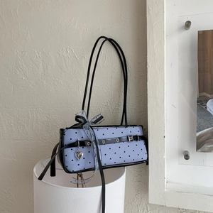 Detail of blue striped baguette bag with heart dots and silver heart charm pendant