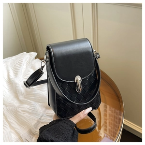 Detail of black woven leather mini bag with silver U-shaped metal clasp on glass table
