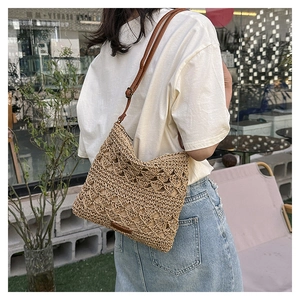 Detail of hand-woven beige straw shoulder bag with leather strap and hollow diamond pattern