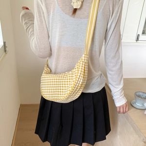 Casual yellow and white checkered canvas dumpling bag with striped strap on female model
