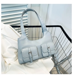Detail of light blue faux leather shoulder bag with decorative double pockets and silver buckles
