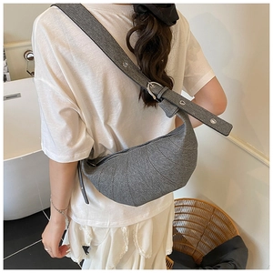 Detail view of a gray quilted croissant bag with a wide adjustable eyelet shoulder strap