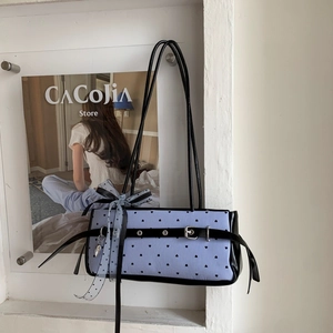 Close-up of blue striped shoulder bag with heart prints and polka dot ribbon bow