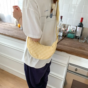 Detail of yellow checkered half-moon canvas bag showing adjustable wide shoulder strap