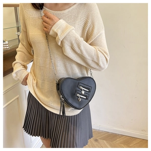Detail of heart-shaped crossbody bag with silver zippers and elegant leather tassels