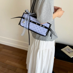 Close-up of blue striped bag with black heart prints and large polka dot mesh bow