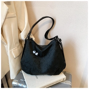 Close-up of black embossed shoulder bag with unique white decorative beads on zipper
