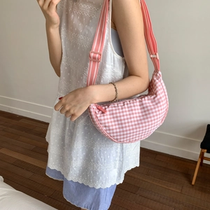 Detail of pink and white gingham crescent crossbody bag with striped adjustable strap